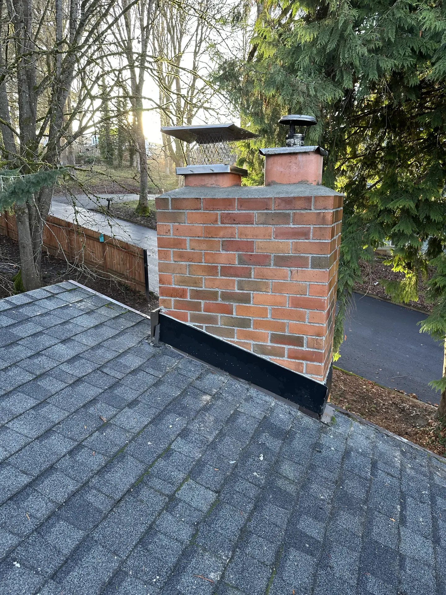 Fresh black counterflashing sealed around a rebuilt brick chimney by First Rate Chimney